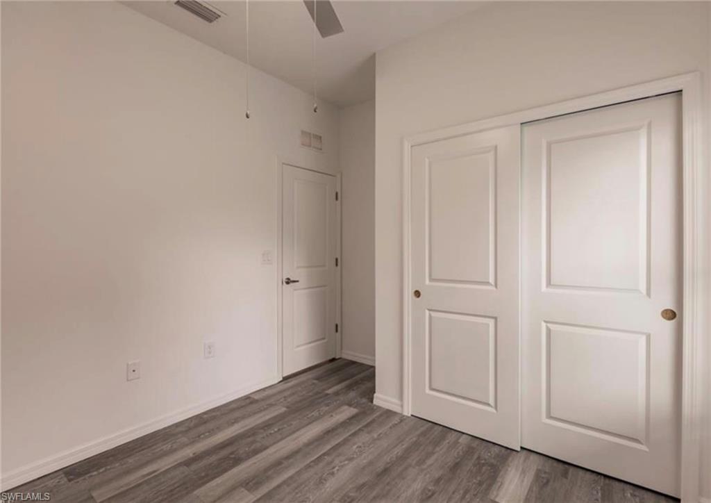 Room featuring wood-finish flooring, a ceiling fan, and white walls