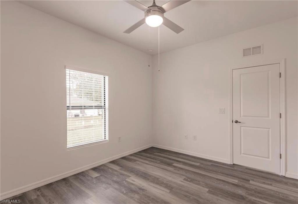Bright room featuring wood-finish flooring, a contemporary ceiling fan with integrated lighting, and a white paneled door