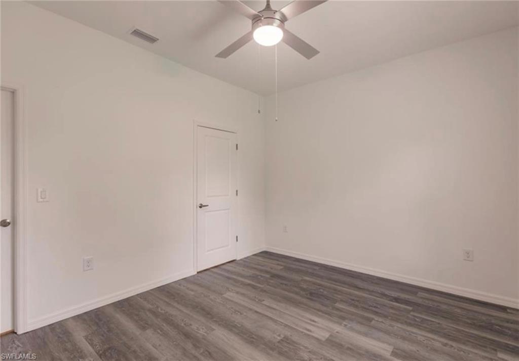 Room featuring wood-finish flooring, white baseboards, a ceiling fan with integrated lighting, and two panel doors