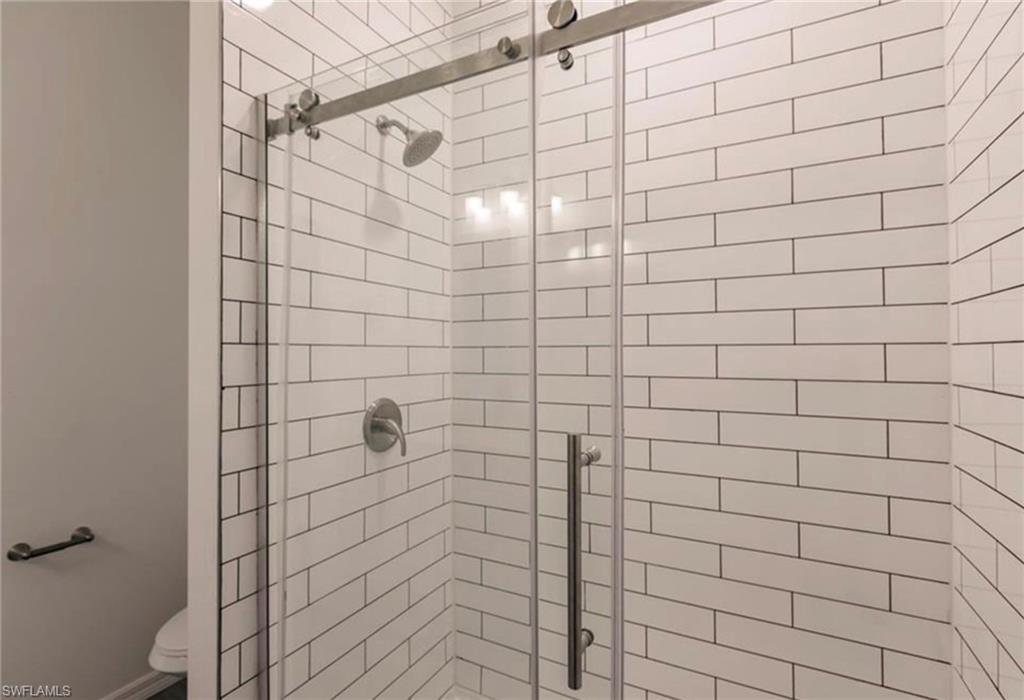 Walk-in shower featuring subway tile surround, brushed nickel hardware, and a glass sliding door