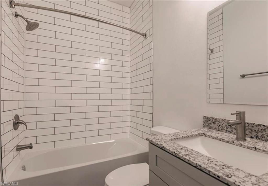 Bathroom featuring subway tile shower surround, bathtub, and a vanity with a speckled countertop, integrated sink, and modern brushed nickel faucet