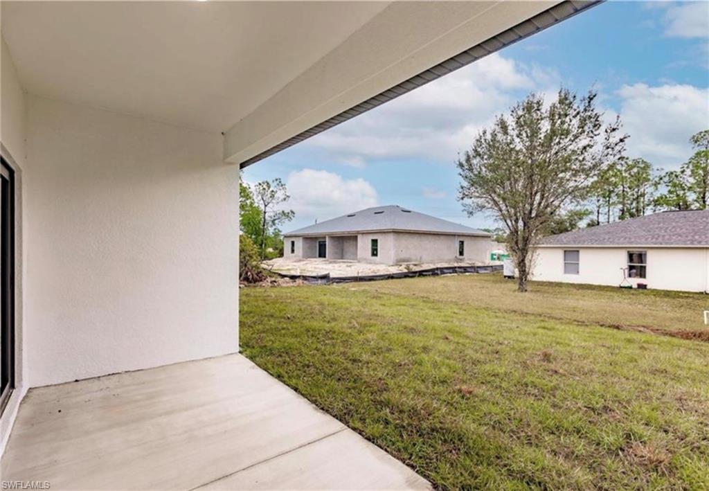 Covered concrete patio extending to a grass lawn