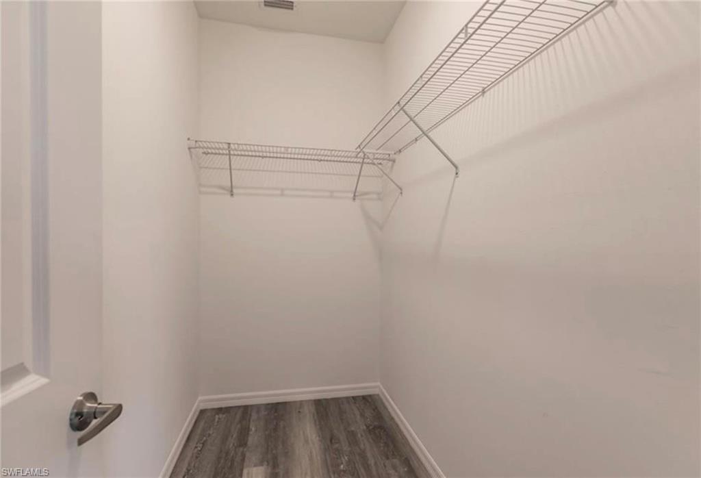 Walk-in closet featuring wire shelving, white painted walls, and wood-finish flooring