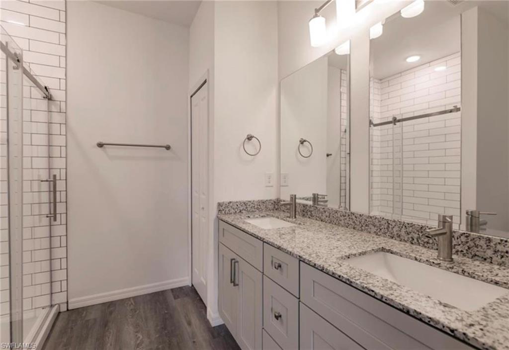 Double vanity with light gray shaker cabinetry, speckled granite countertop, and undermount sinks