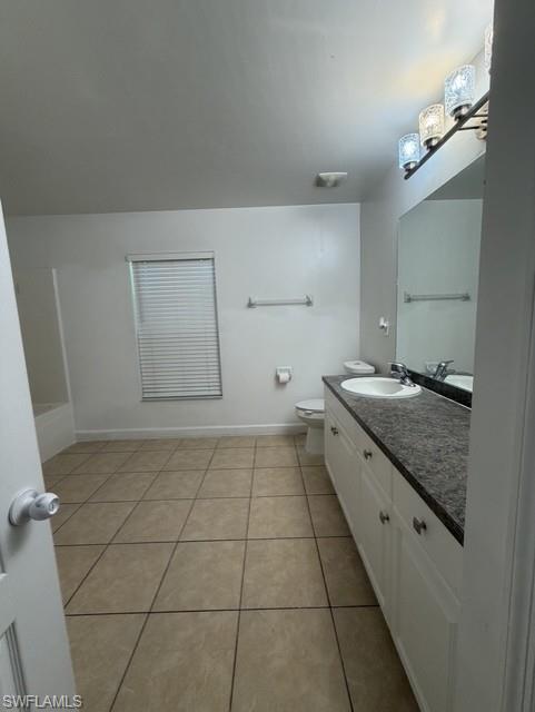 Bathroom featuring a double vanity with white cabinetry, a dark countertop, and a built-in sink