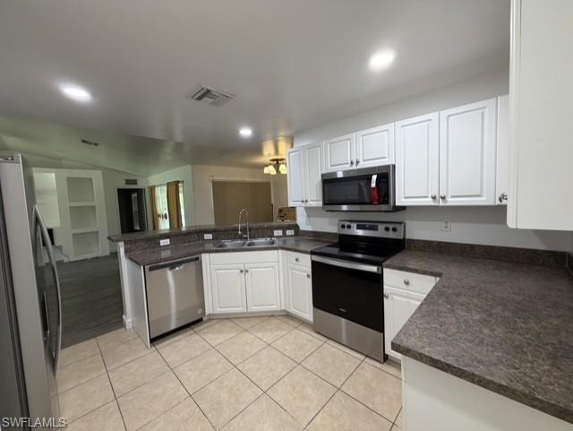 Kitchen featuring white cabinetry, dark speckled countertops, stainless steel appliances, and beige tiled flooring