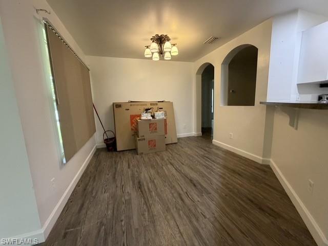 Spacious dining area featuring wood-finish flooring, white baseboards, and a five-light ceiling fixture