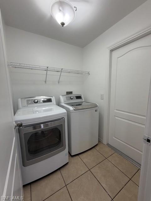 Dedicated utility space featuring tile flooring, white walls, and overhead wire shelving