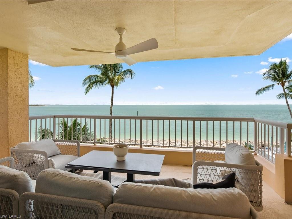 Expansive covered patio featuring a ceiling fan, durable tile flooring, and a metal railing overlooking the waterfront