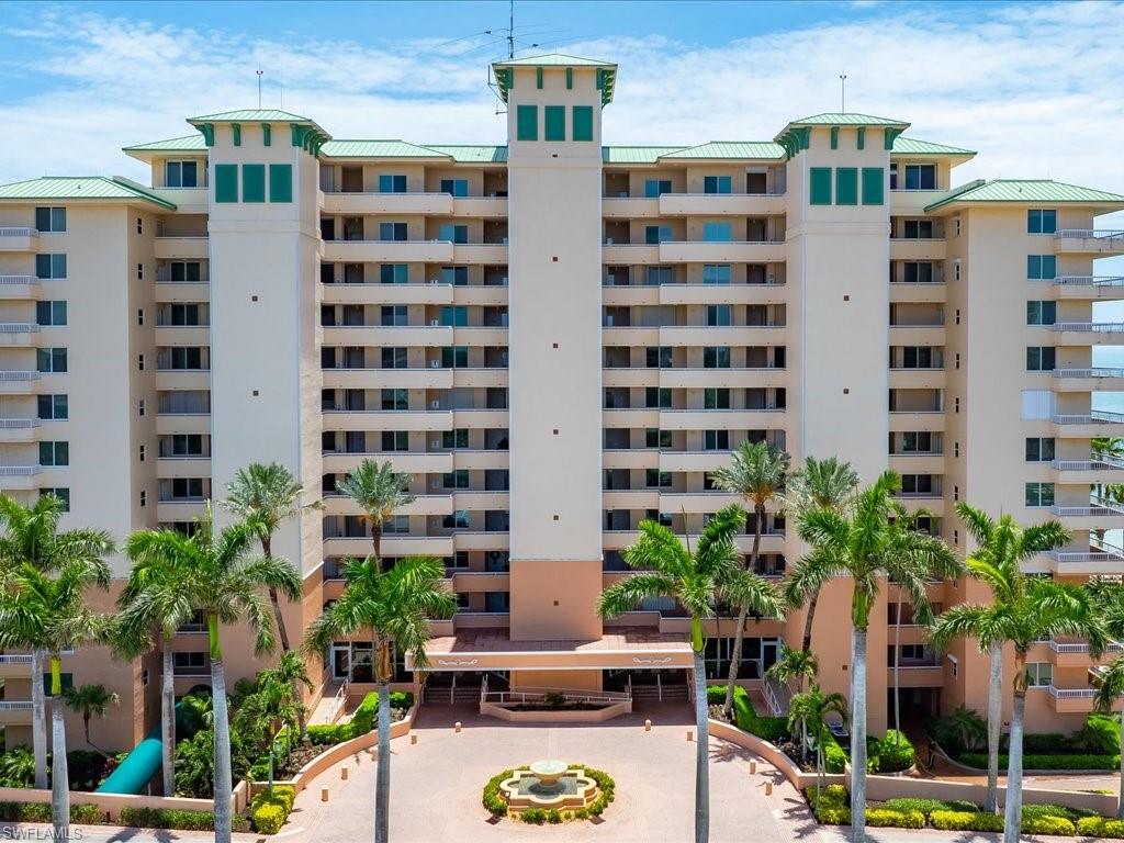 Multi-story condominium building featuring numerous private balconies and a light-toned exterior