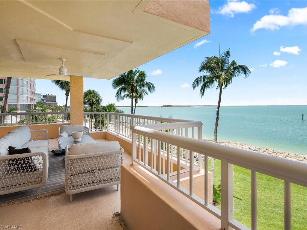 Expansive outdoor living space with water frontage featuring a white railing and a ceiling fan