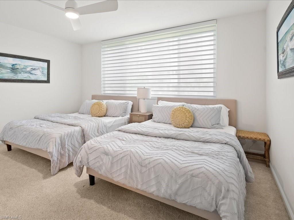 Bedroom featuring neutral carpet flooring, a ceiling fan with integrated lighting, and a large window with horizontal blinds