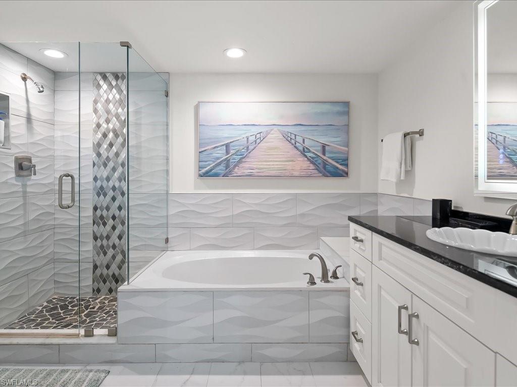 Bathroom featuring a glass-enclosed shower with pebble-tile flooring and a decorative tile accent strip