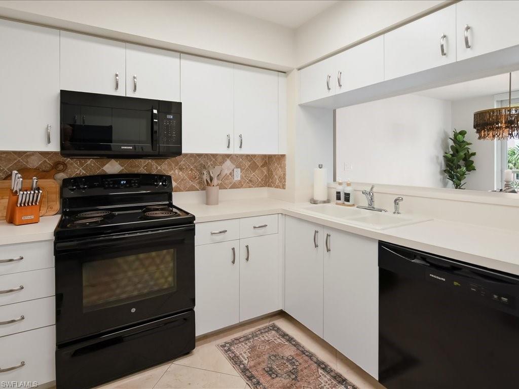 Kitchen featuring white cabinetry with brushed nickel hardware, stone-look countertops, and a tiled backsplash