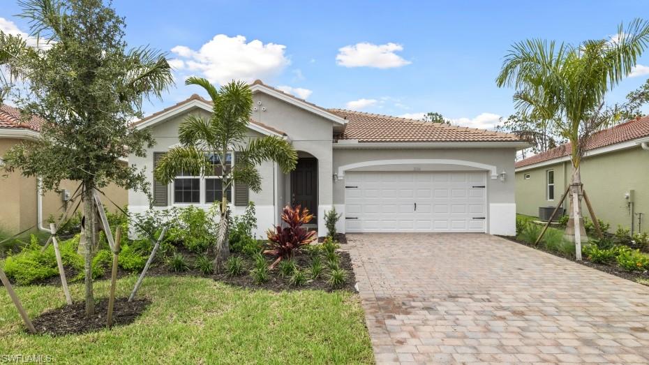 Single-story residence featuring a tile roof, light gray stucco exterior, and a paver driveway