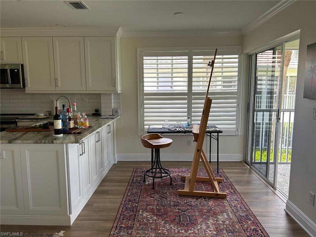 Kitchen featuring healthy amount of natural light, white cabinets, dark stone countertops, and crown molding