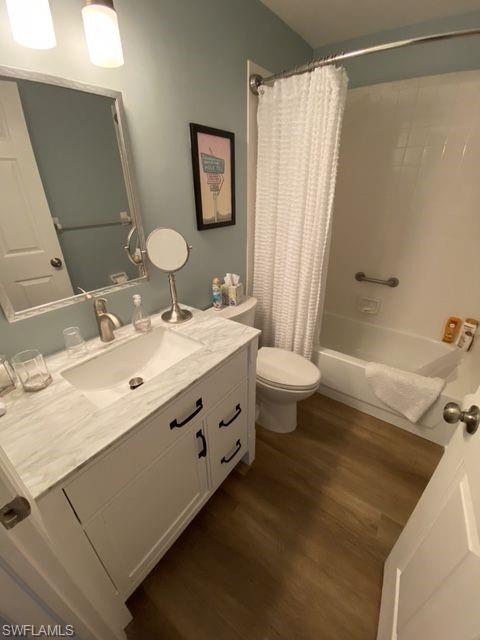Full bath featuring shower / bathtub combination with curtain, dark wood-style flooring, and vanity