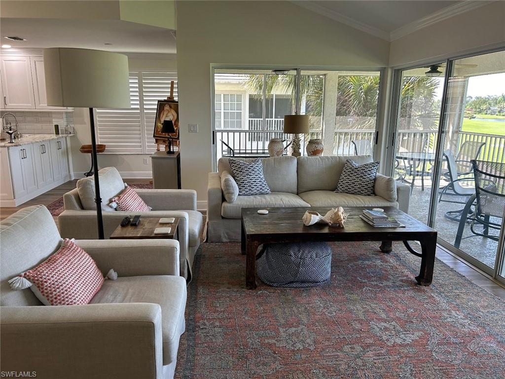 Living room featuring plenty of natural light, dark wood-style flooring, vaulted ceiling, and ornamental molding