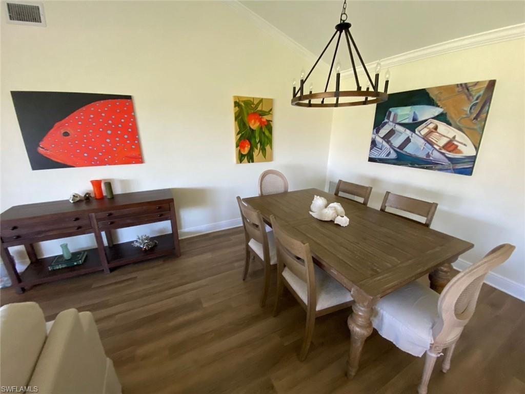 Dining room featuring dark wood-style floors, ornamental molding, and a chandelier