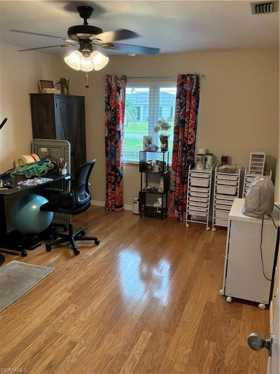 Room featuring wood-finish flooring, a ceiling fan with integrated lighting, and a window with blinds