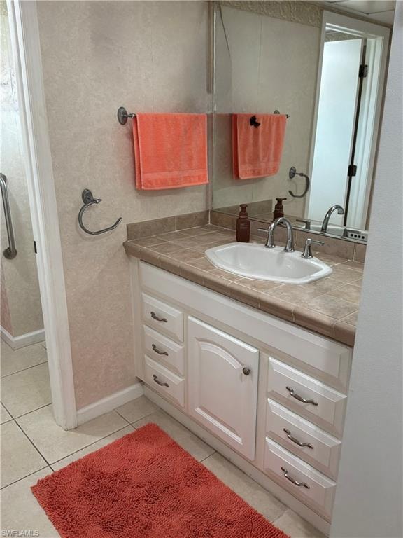 Bathroom vanity featuring a single basin sink with chrome fixtures, tiled countertop, and white cabinetry with drawer storage