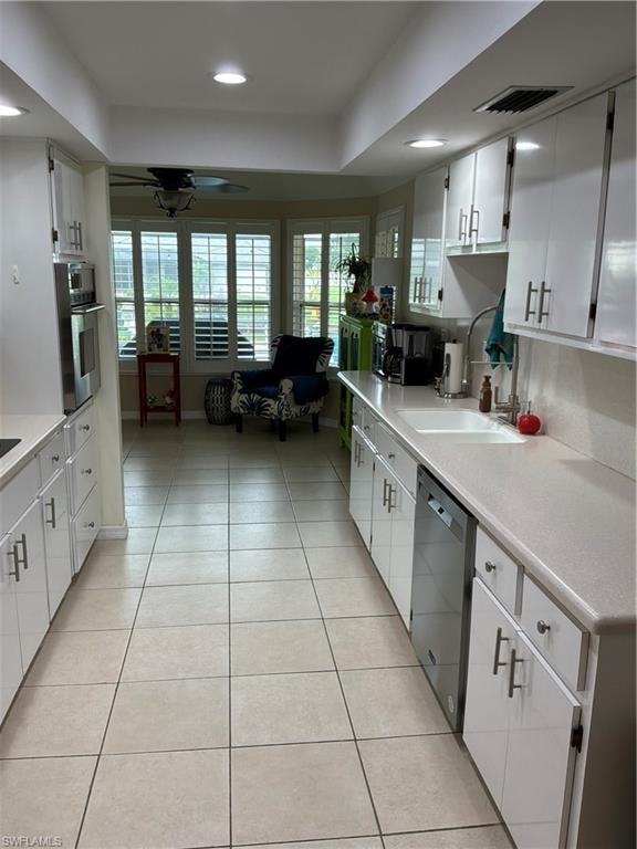 Galley kitchen featuring white cabinetry, light-toned countertops, and tile flooring