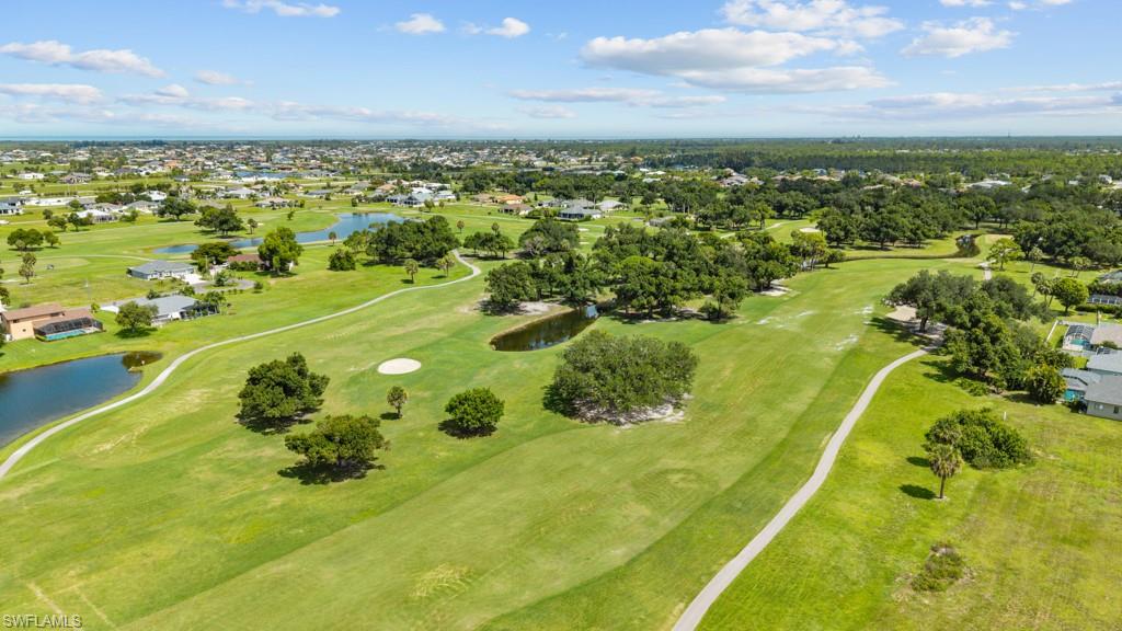 Expansive golf course landscape featuring lush green fairways, scattered mature trees, and several water hazards
