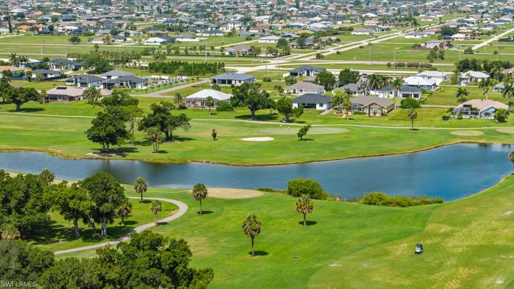 Expansive golf course with manicured greens, a prominent water feature, and mature trees