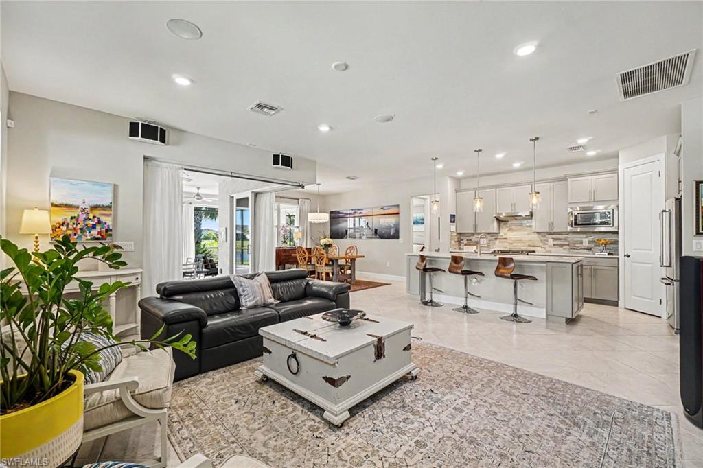 Spacious open-concept living area featuring light-toned tile flooring, recessed lighting, and sliding glass doors to the exterior