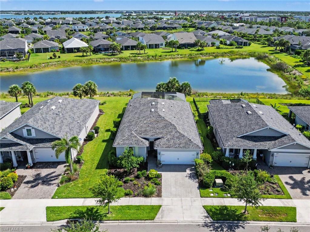 Residential property with a water feature backdrop, featuring a gray shingle roof, a two-car garage, and established landscaping