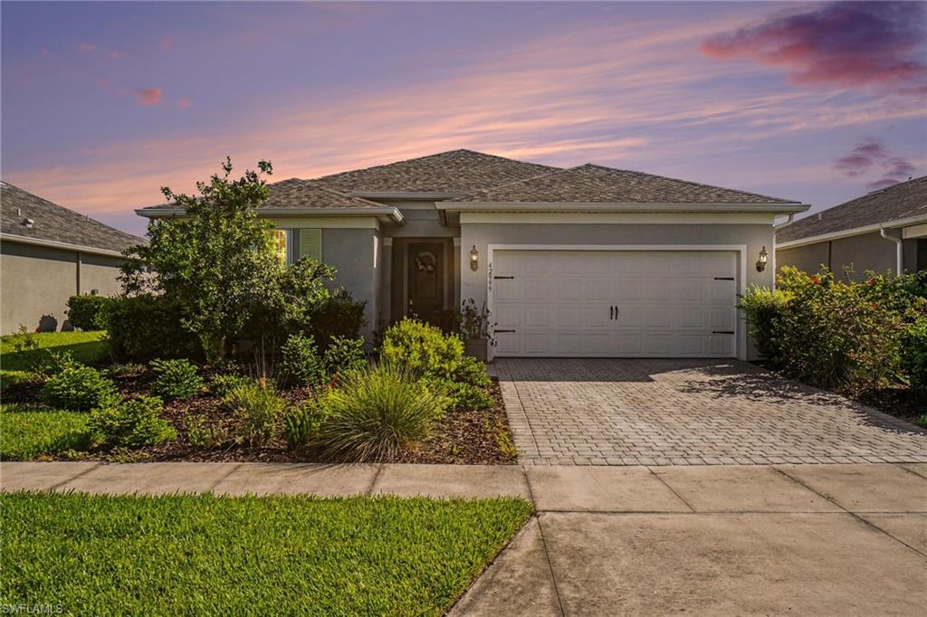 One-story residence featuring a gray exterior, a two-car garage with carriage-style hardware, and a paver driveway