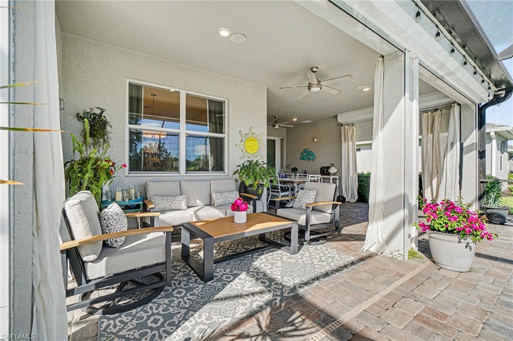 Expansive covered patio featuring brick paver flooring, multiple ceiling fans, recessed lighting, and large windows