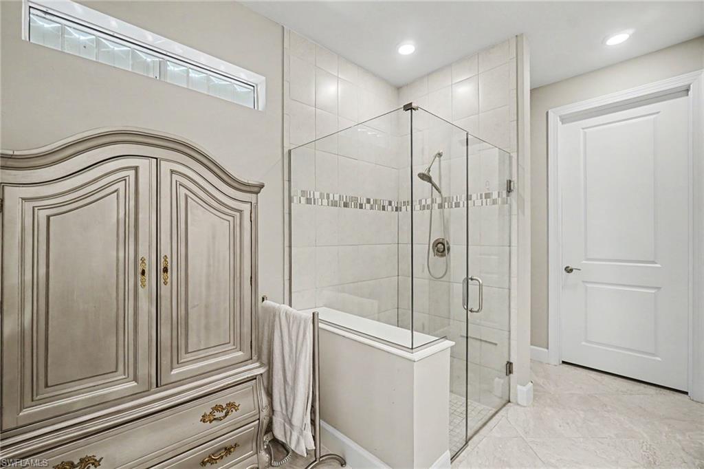 Glass-enclosed shower featuring white subway tile, a decorative mosaic accent band, and recessed lighting