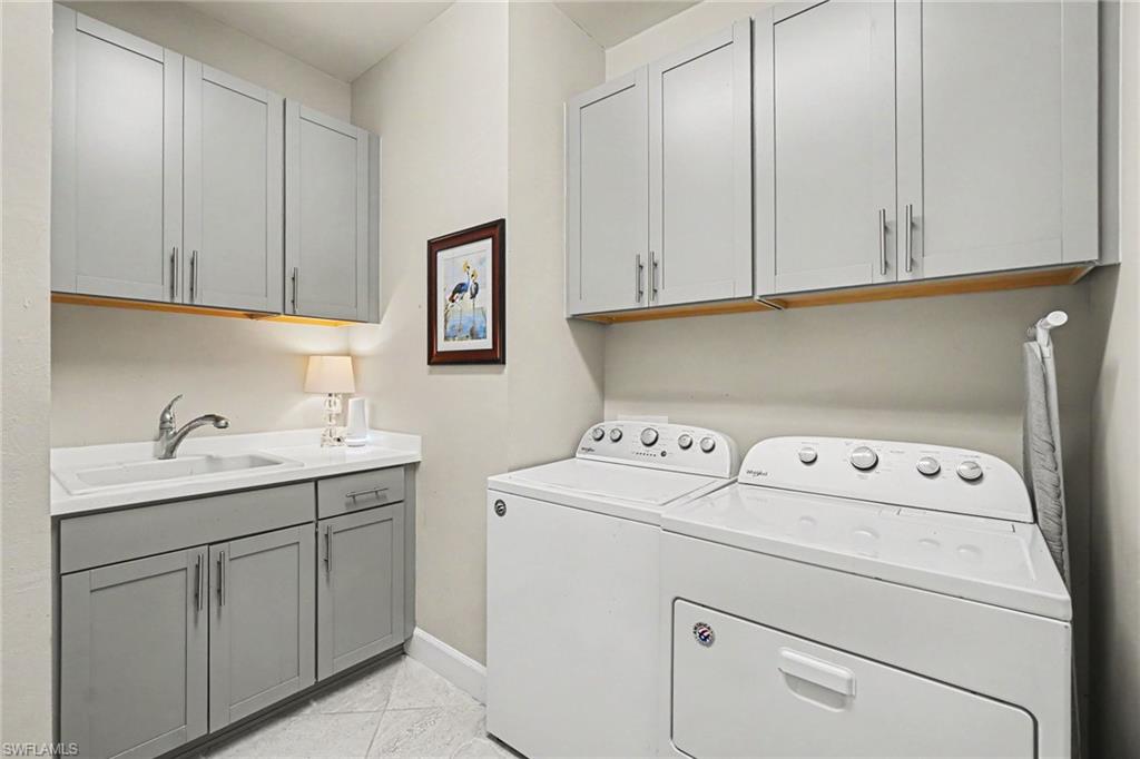 Laundry room with ample grey cabinetry, a built-in sink, and under-cabinet lighting