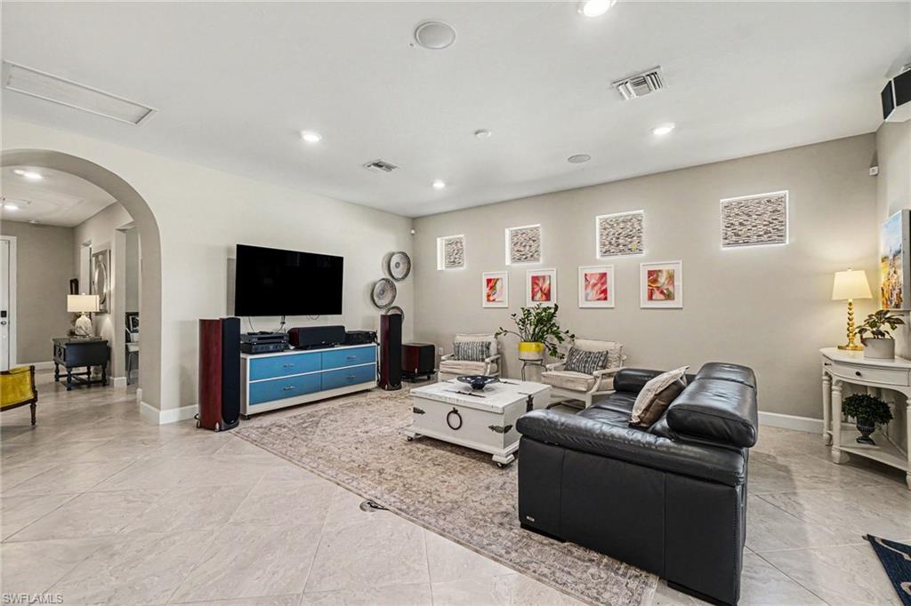 Expansive living area featuring large format tile flooring, recessed lighting, an arched entryway, and a built-in wall niche with integrated lighting