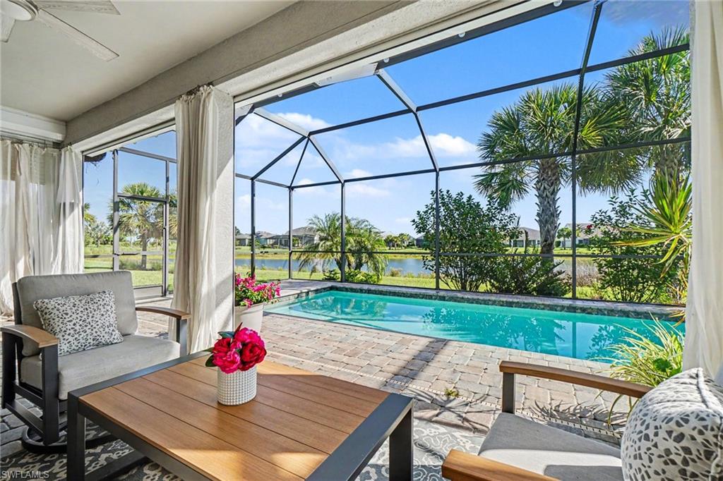Screened lanai featuring a private pool with brick paver decking, overlooking a body of water and tropical landscaping