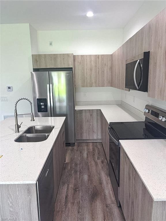 Modern kitchen featuring wood-finish cabinetry, light speckled countertops, and stainless steel appliances