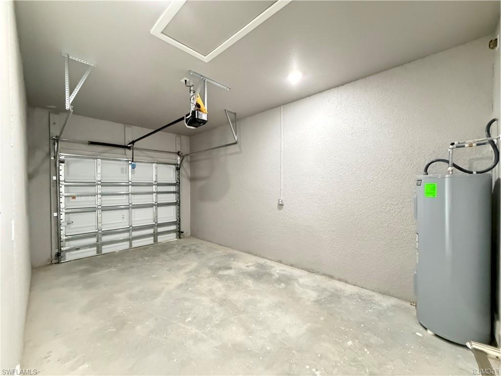 Attached garage featuring a concrete floor, automatic garage door opener, and water heater installation