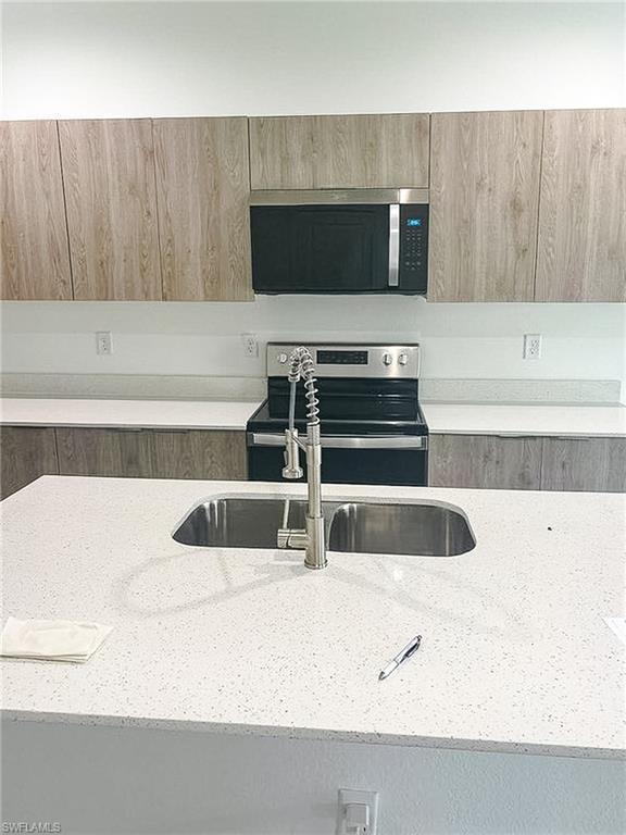 Kitchen featuring a large light-toned speckled countertop with an undermount double-basin stainless steel sink and a brushed nickel gooseneck faucet