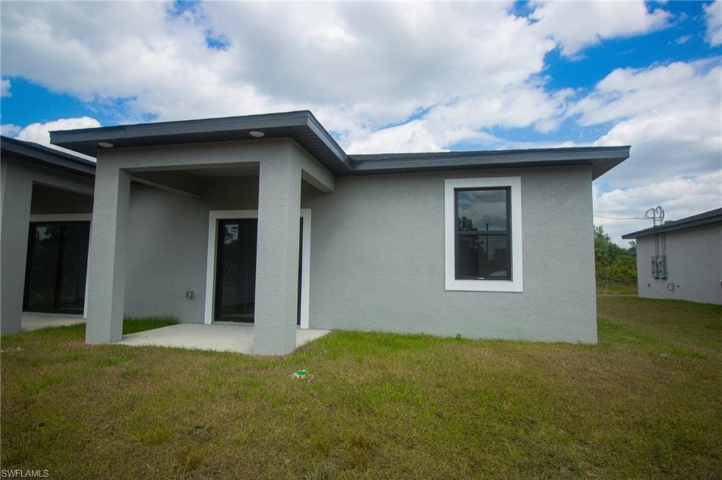 Contemporary exterior featuring a covered entry porch with recessed lighting, gray stucco finish, dark-framed windows, white window trim, and a dark roofline