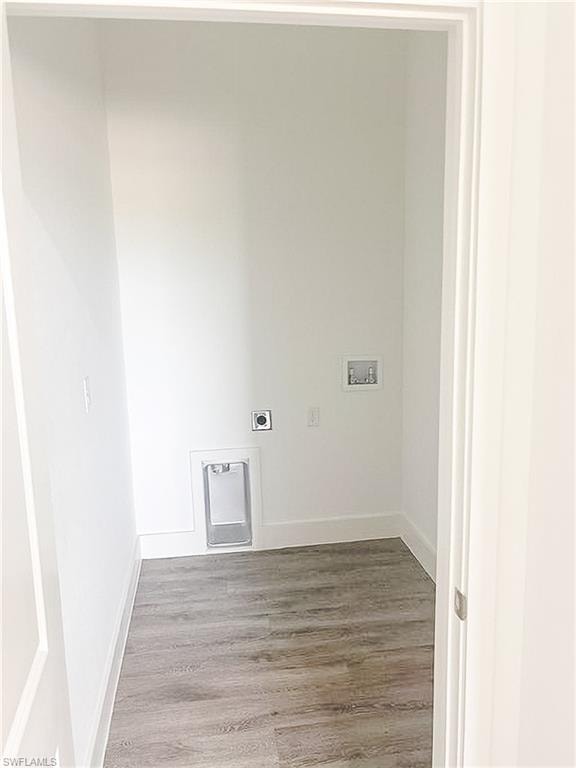 Utility space featuring wood-finish flooring, white walls, and bright baseboards