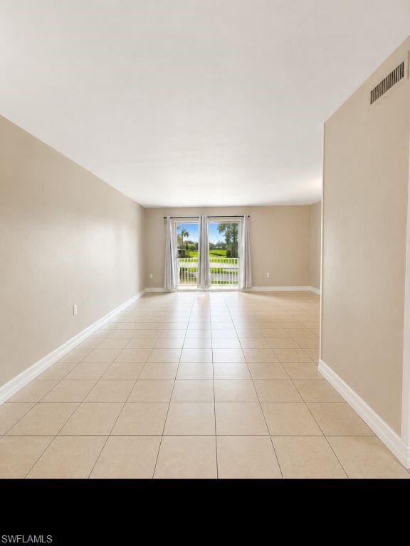 Spacious room featuring neutral wall tones and large format tile flooring