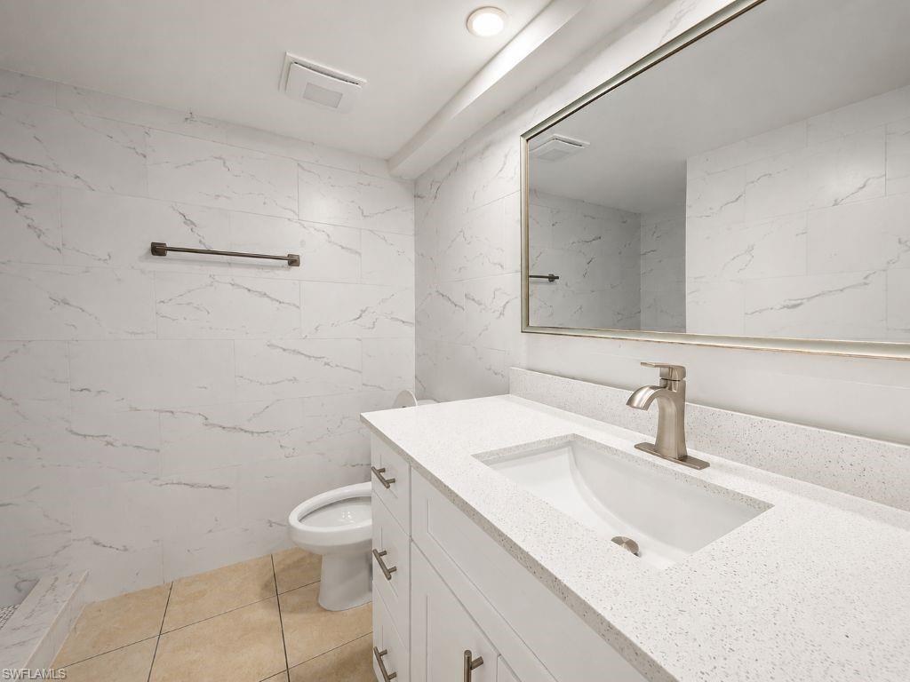White vanity with an integrated sink and brushed nickel faucet, set against a large framed mirror