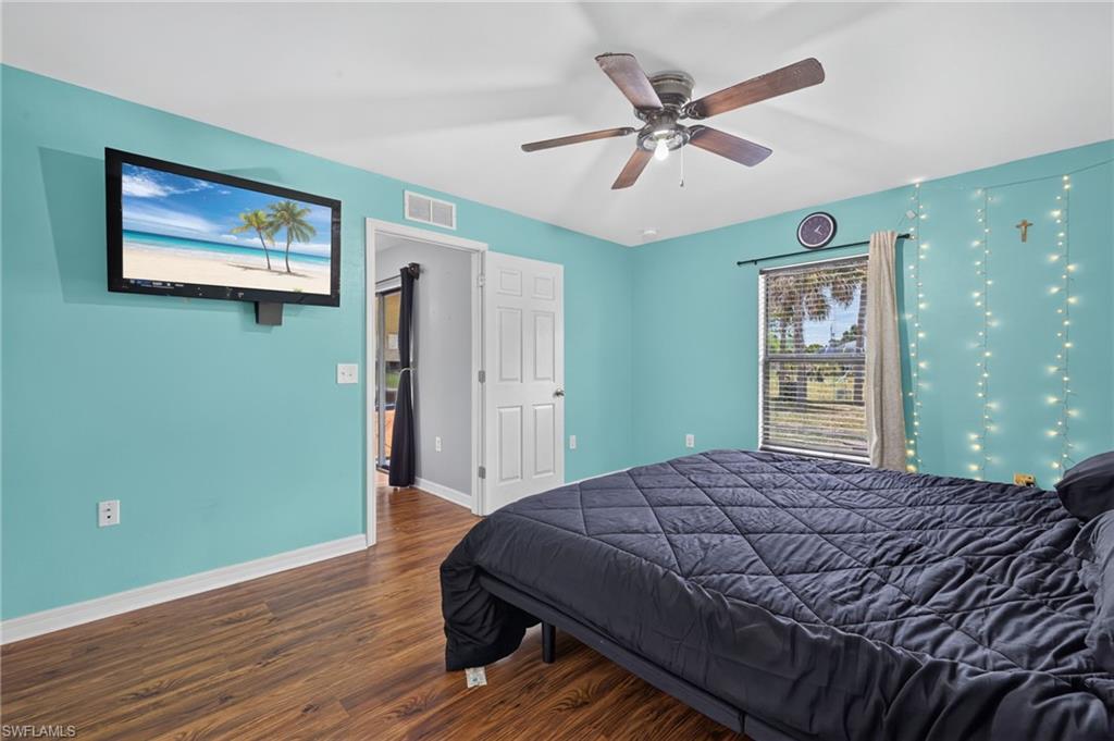 Room featuring wood-finish flooring, a ceiling fan with light, and a window with horizontal blinds