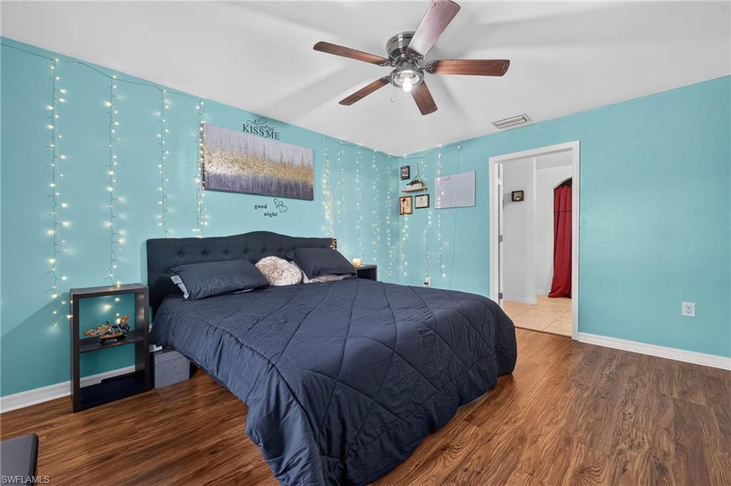 Spacious room featuring wood-finish flooring, a ceiling fan, and a wide entryway