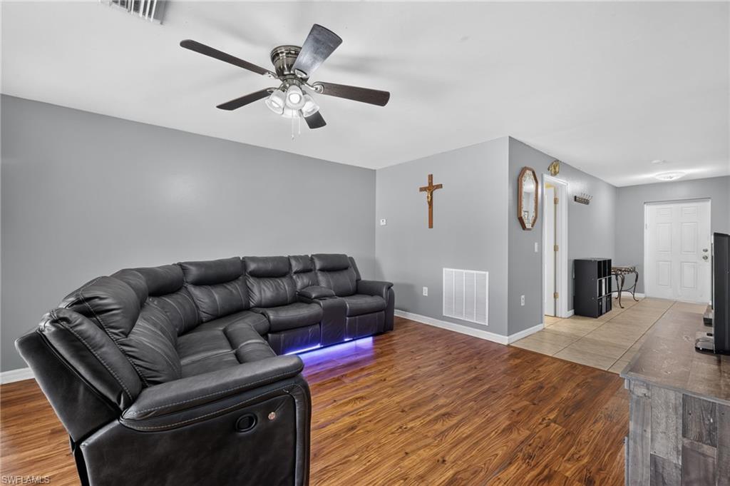Living area featuring wood-finish flooring, a ceiling fan with integrated lighting, and neutral wall tones