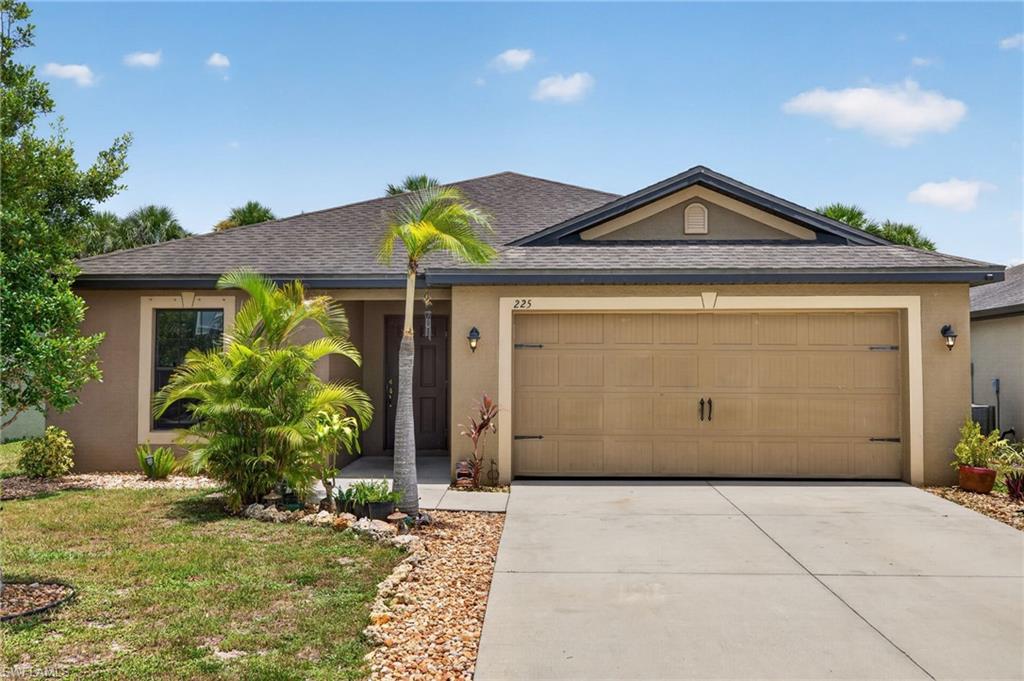 Contemporary stucco home featuring a two-car garage with carriage-style doors, a concrete driveway, and a gravel-edged walkway