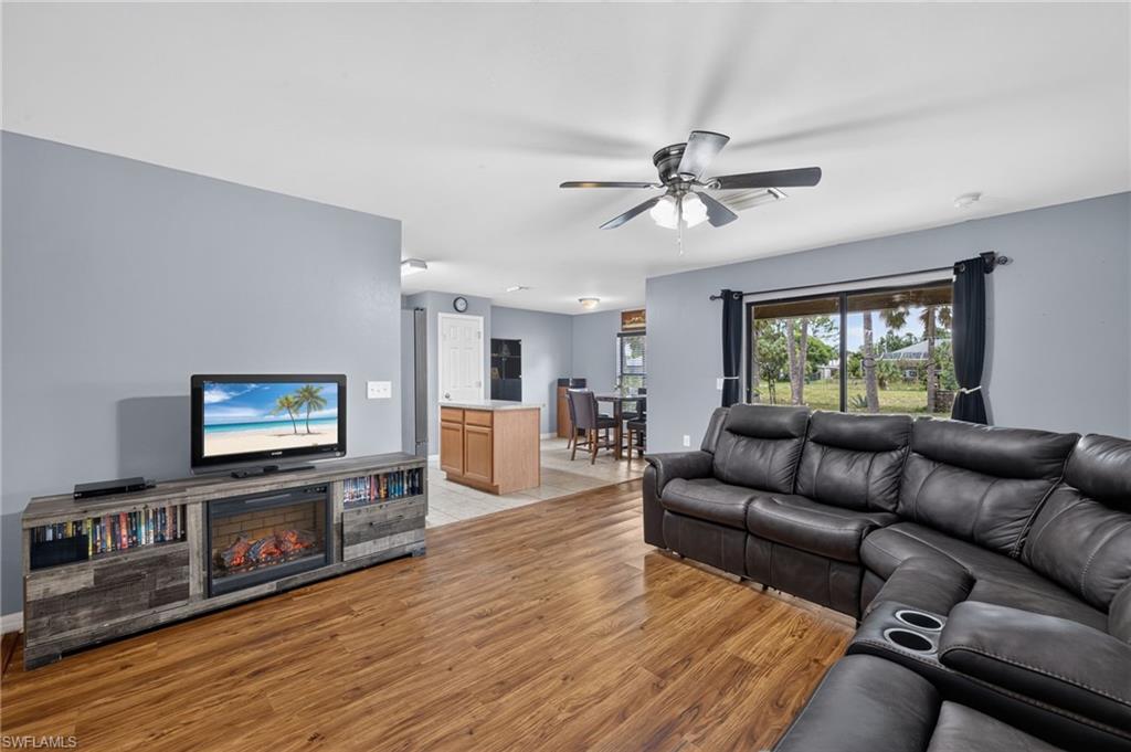 Spacious living area featuring wood-finish flooring, a ceiling fan, and ample natural light from a large window