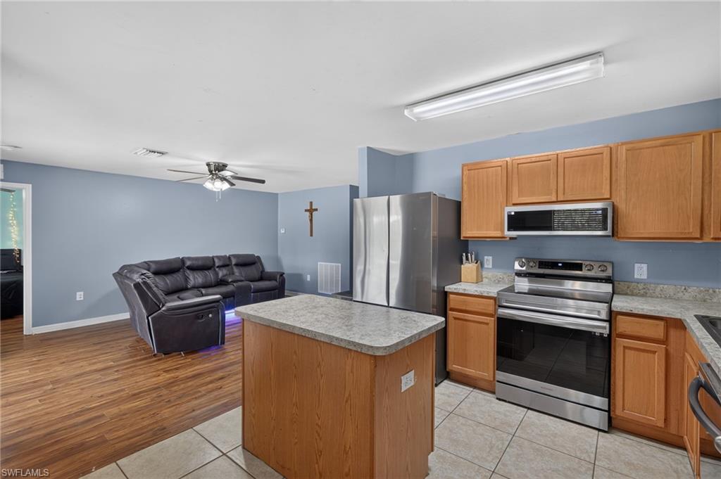 Kitchen featuring wood cabinetry, stainless steel appliances, and an island with counter seating