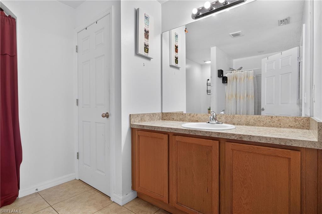 Bathroom vanity featuring a light-toned countertop with integrated sink, wood-finish cabinetry, and a large wall-mounted mirror